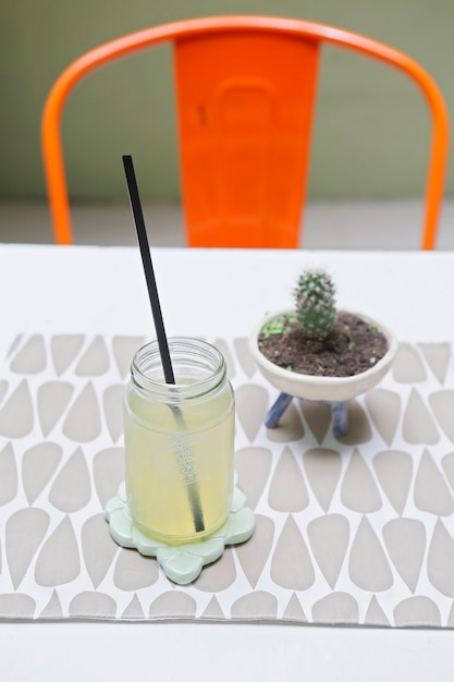 Tarro con limonada y un cactus sobre la mesa con una silla roja