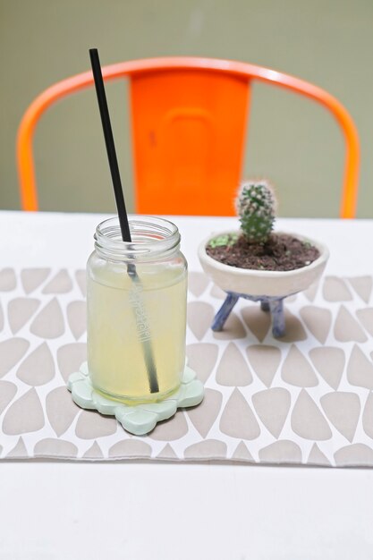 Tarro con limonada y un cactus sobre la mesa con una silla roja