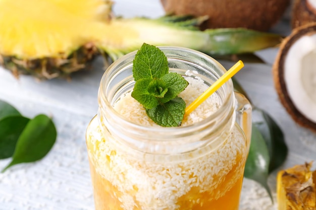 Tarro de masón con cóctel de piña en mesa de madera