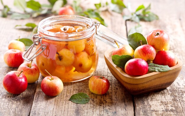 Tarro de mermelada de manzana con frutas frescas en la mesa de madera