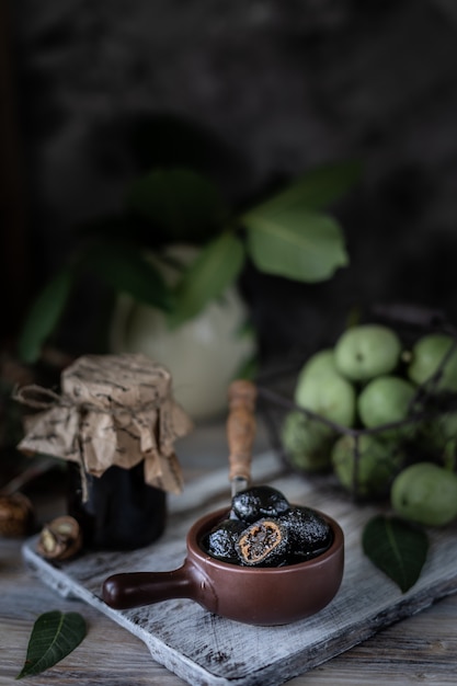 Tarro de mermelada de nuez en una mesa de madera y un grupo de nueces verdes.