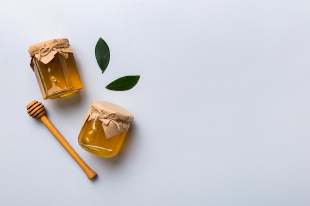 Tarro de miel con cucharón de miel de madera sobre fondo blanco vista superior con espacio de copia Botella de miel deliciosa