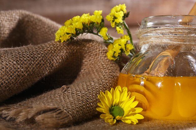 Tarro de miel con flores en cilicio closeup