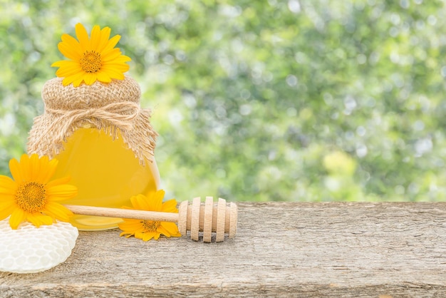 Un tarro de miel con flores sobre un fondo desenfocado con espacio para copiar