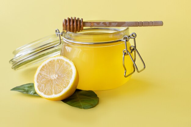 Tarro de miel con limón sobre fondo amarillo