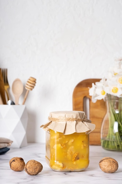 Tarro con miel de nueces en el interior de la cocina con flores.