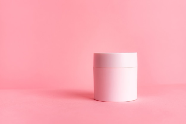 tarro rosa con crema sobre una superficie rosa. cosmetología. protección de la piel.