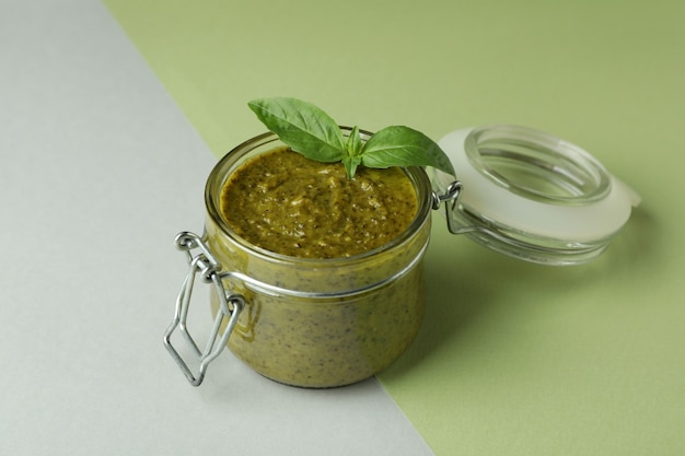 Tarro de salsa pesto sobre fondo de dos tonos