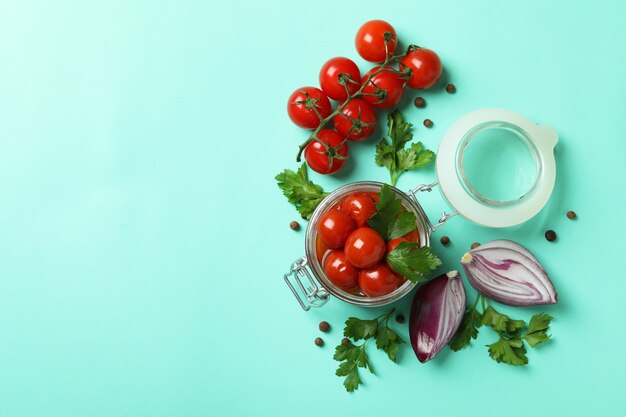 Tarro con tomates en escabeche e ingredientes sobre fondo de menta