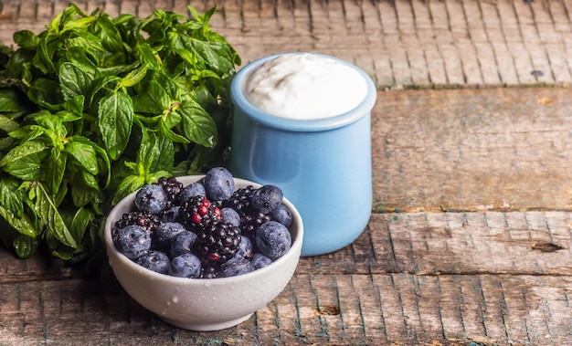 Un tarro de yogur casero y un cuenco de arándanos.