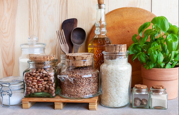 Tarros de cereales, utensilios de cocina y plantas domésticas. Entorno saludable, cocina cómoda, concepto de estilo de vida sostenible.