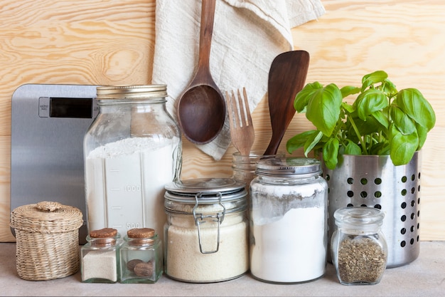 Tarros de cereales, utensilios de cocina y plantas domésticas. Entorno saludable, cocina cómoda, concepto de estilo de vida sostenible.