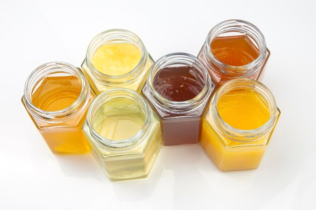 Tarros hexagonales con diferentes tipos y colores de miel de flores frescas. alimento vitamínico para la salud y la vida