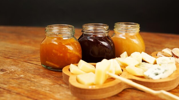 Tarros de mermeladas caseras y una variedad de quesos sobre una mesa de madera Plato de queso