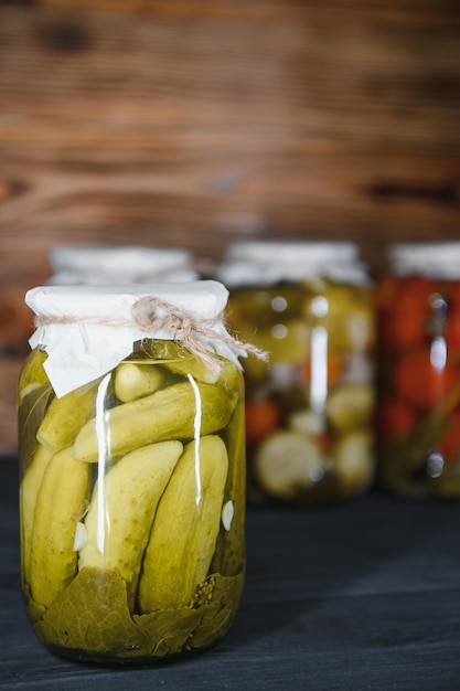 Tarros de verduras encurtidas sobre fondo de madera rústica