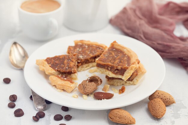 Tarta de almendras en plato pequeño y taza de café