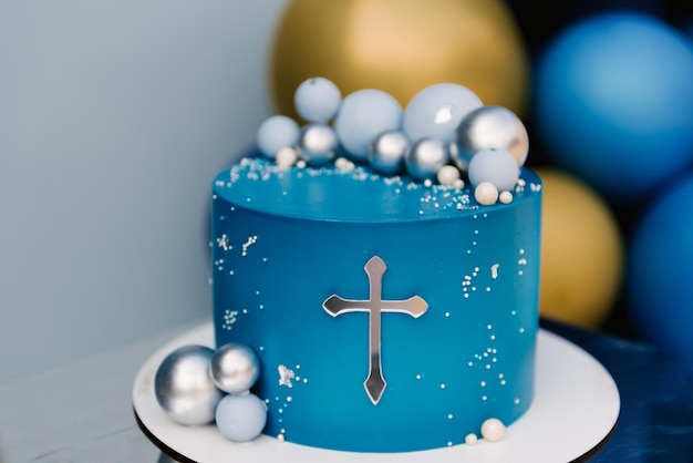 Foto tarta azul festiva con diseño de globos y tarta de bautizo con cruz plateada