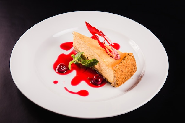 Tarta de bayas con decoración en una placa redonda blanca sobre fondo negro