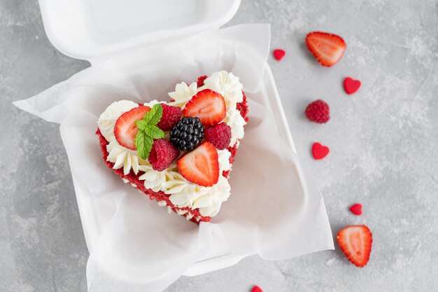 Tarta bento de terciopelo rojo pequeña tarta en una lonchera sobre un fondo de hormigón gris