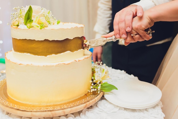 Foto tarta de boda blanca de tres niveles decorada con flores de mástica en una mesa de madera blanca imagen para un menú o un catálogo de confitería con espacio para copiar