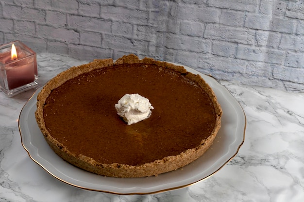 Tarta de calabaza casera, con crema y porción rota sobre fondo claro, postre de acción de gracias