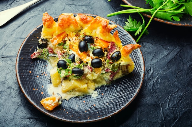 Tarta casera con aceitunas, champiñones y salchicha.