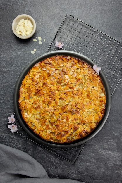 Tarta casera de almendras con corteza de almendras en rodajas sobre superficie oscura