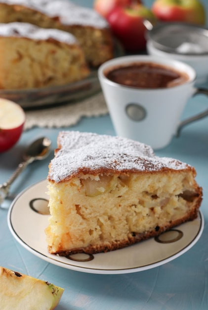 Tarta casera Charlotte con manzanas y taza de café sobre fondo azul claro