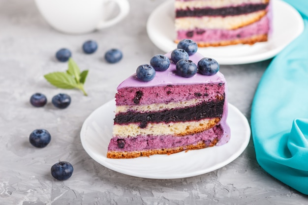 Tarta casera con crema de soufflé y mermelada de arándanos con una taza de café sobre una superficie de hormigón gris. vista lateral.