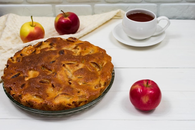 Tarta casera de manzana al horno en un plato sobre una mesa blanca de madera lista para comer Lugar para una inscripción
