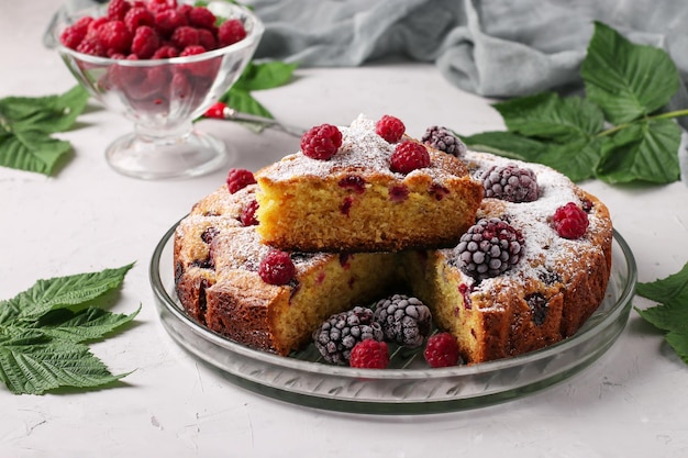 Tarta casera de moras y frambuesas con un trozo en un plato en formato horizontal de fondo gris claro