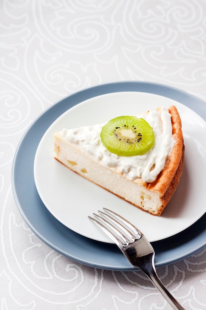 Tarta casera de requesón con kiwi y crema en un plato