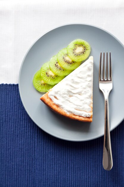 Tarta casera de requesón y sémola con kiwi y crema en un plato