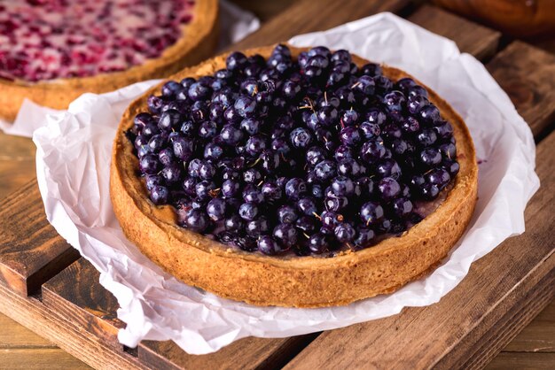 Tarta casera de tarta de arándanos sabrosa decorada con fondo de madera de postre de bayas maduras