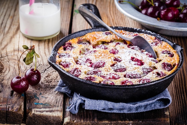 Tarta de cereza Clafoutis sobre fondo de madera rústica