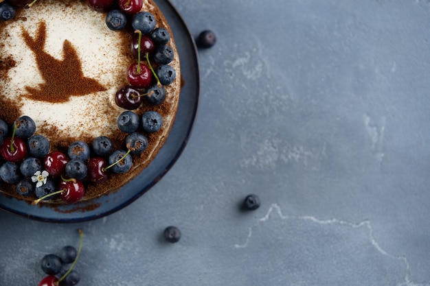 Tarta de cerezas de pájaro de tres capas con crema agria decorada con bayas y cerezas frescas