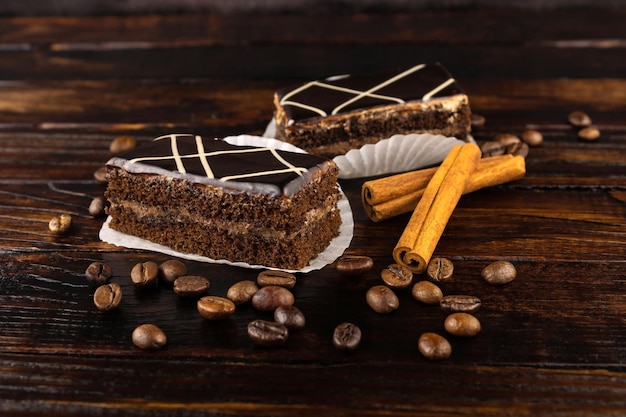 Tarta de chocolate con granos de café y palitos de canela sobre un fondo de madera