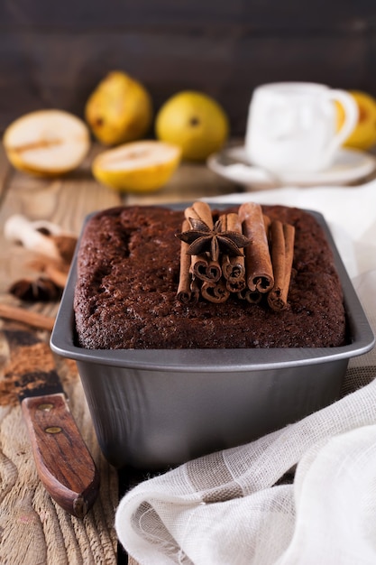 Tarta de chocolate con peras y canela sobre la mesa de madera antigua.