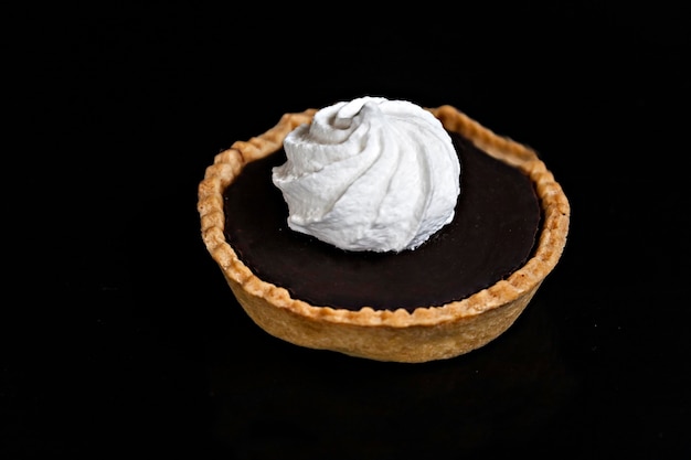 Tarta de chocolate con tartaleta de merengue en un primer plano aislado de fondo negro