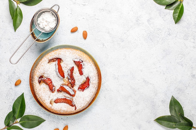 Tarta de ciruela rústica casera con azúcar en polvo y almendras, vista superior