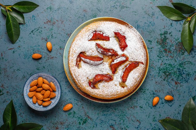 Tarta de ciruela rústica casera con azúcar en polvo y almendras, vista superior