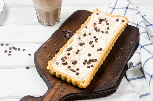 Tarta con crema de vainilla o tarta de queso con gotas de chocolate y taza de café