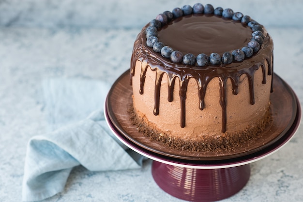 Tarta de cumpleaños de chocolate con arándanos y glaseado de chocolate sobre un fondo claro