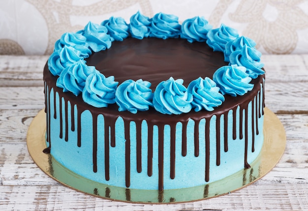 Foto tarta de cumpleaños con crema de chocolate gotea sobre un fondo blanco.