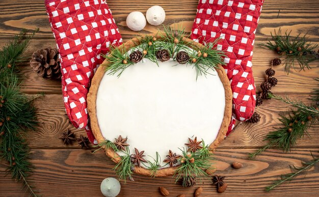 Tarta festiva con crema blanca decorada con conos, ramas de coníferas y anís estrellado. Concepto de año nuevo y Navidad. Copie el espacio y la vista superior.