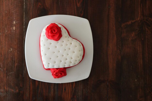 Tarta de fondant en forma de corazón sobre una mesa de madera