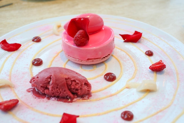 tarta de frambuesa en un plato con helado de frambuesa y pétalos de rosa