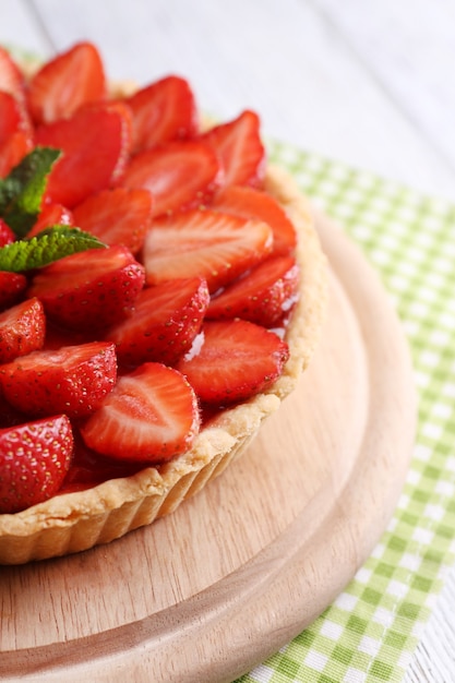 Tarta de fresa en bandeja de madera sobre fondo de madera de color