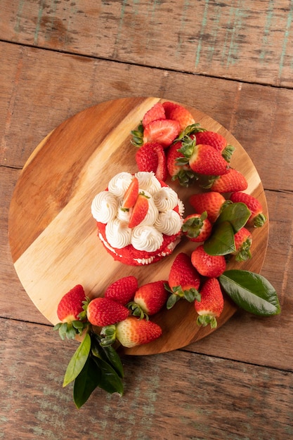 Tarta de fresa con crema de chocolate blanco y fresas alrededor de la vista de la mesa rústica