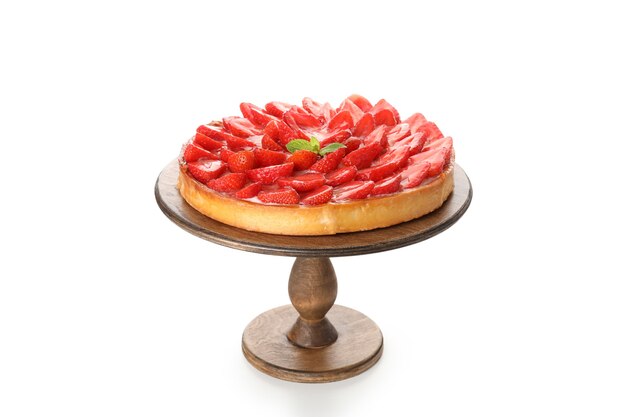 Tarta de fresa sobre soporte de madera aislado sobre fondo blanco.